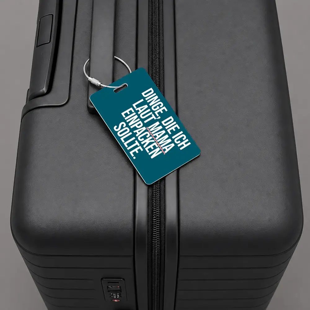 Close-up of a black hard-shell suitcase with a teal luggage tag attached to the zipper.