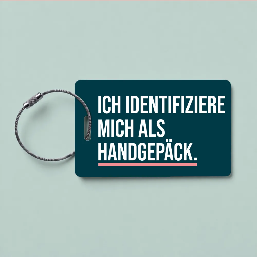 Luggage tag on a metal loop, with bold white German text 'ICH IDENTIFIZIERE MICH ALS HANDGEPACK.' on a dark teal background.