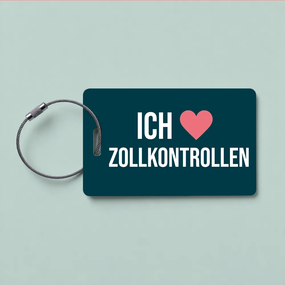 Dark teal luggage tag reading 'ICH ❤️ ZOLLKONTROLLEN' with a metal looped cable.