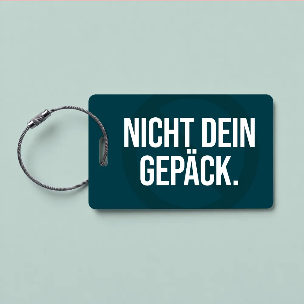 Teal luggage tag with a bold white slogan 'NICHT DEIN GEPÄCK' and a metal loop on the left side.
