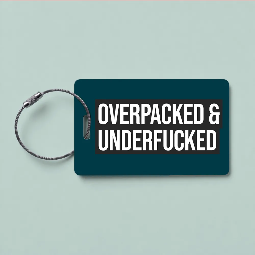 Teal luggage tag with a metal loop, displaying the bold text: 'OVERPACKED & UNDERFUCKED' on a dark background.