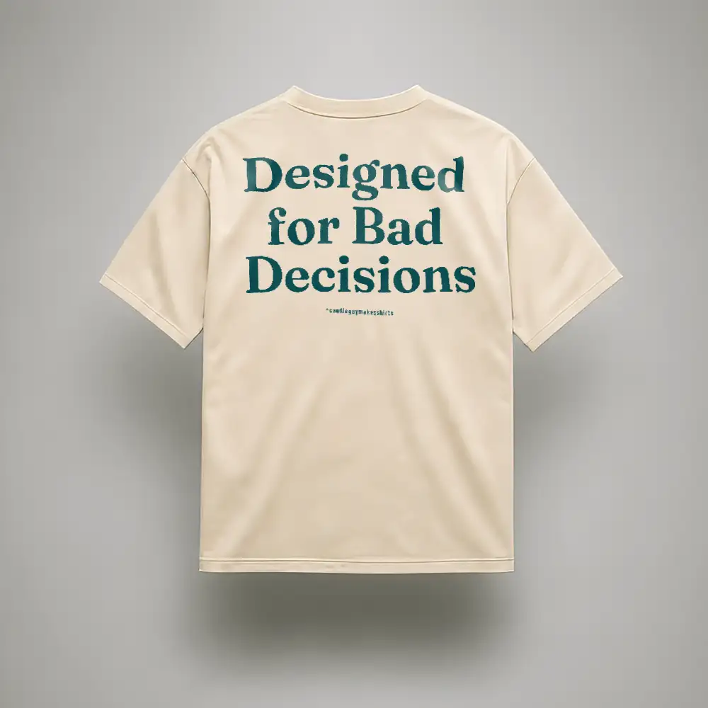 Back view of a beige T-shirt with teal text: "Designed for Bad Decisions" on the back.