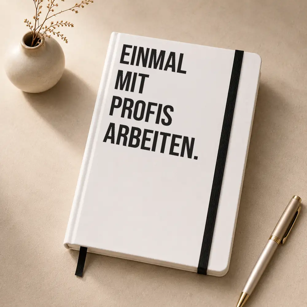 Notizbuch mit dem Spruch „Einmal mit Profis arbeiten“ auf einem Schreibtisch