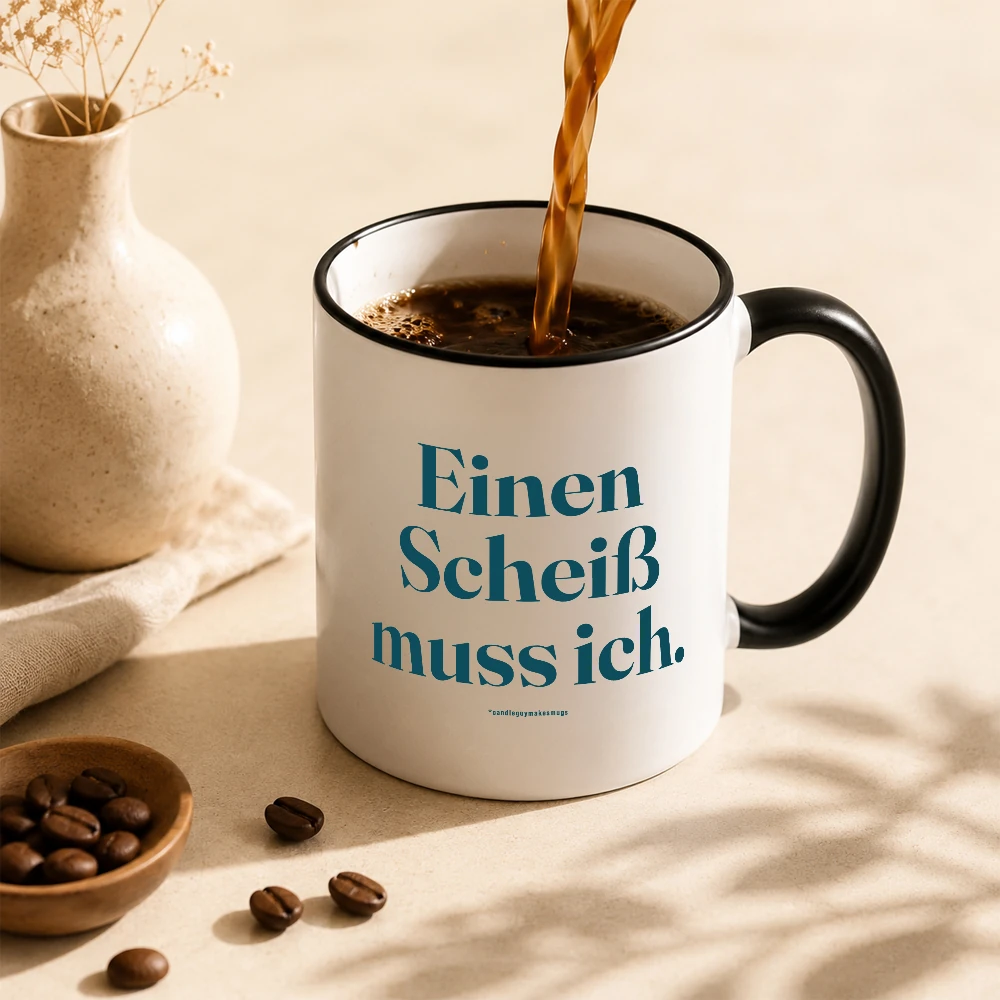 White mug with teal German text 'Einen Scheiß muss ich.' as hot coffee is poured into it.